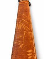 Detail van cognac leren halsband met zichtbare oppervlakkige krasjes op witte achtergrond