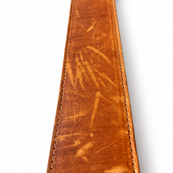 Detail van cognac leren halsband met zichtbare oppervlakkige krasjes op witte achtergrond